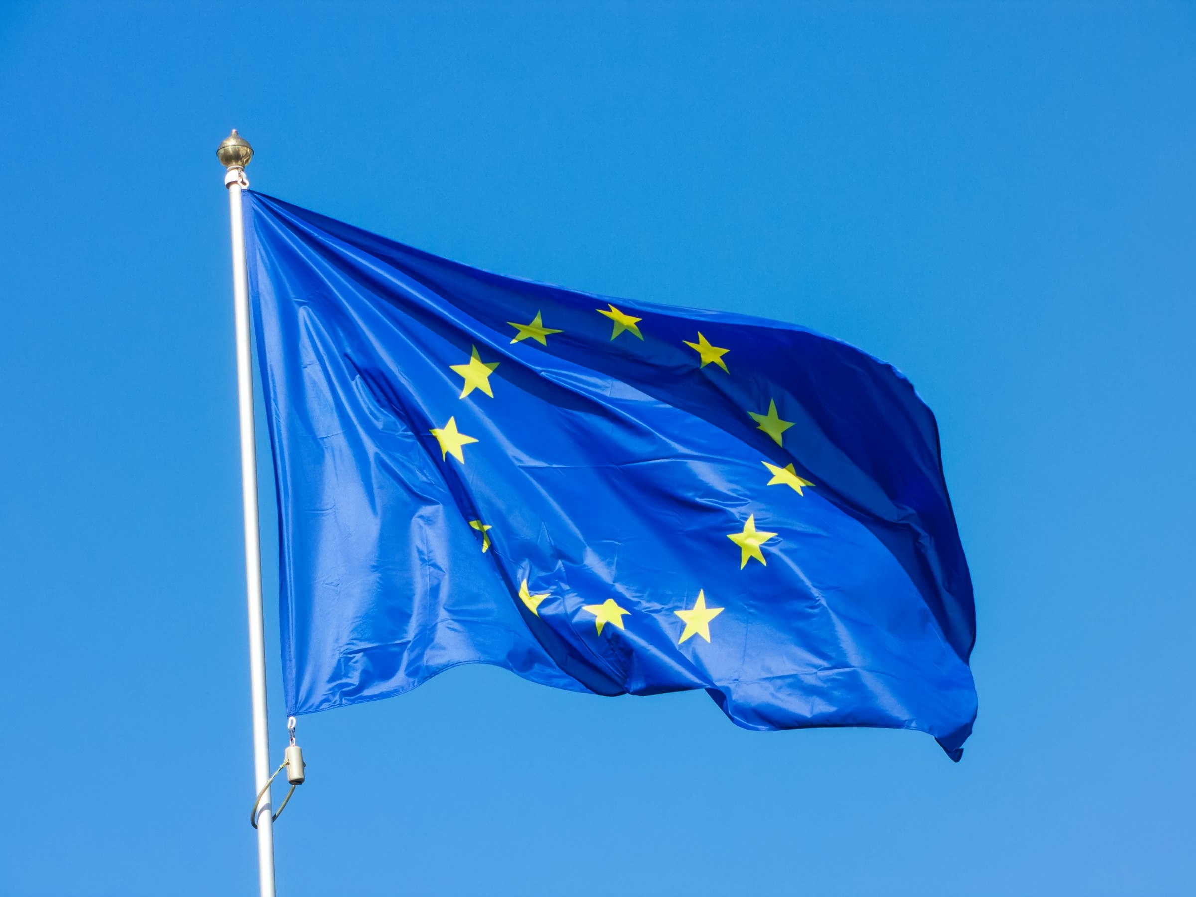 Bandiera dell'Unione Europea che sventola contro un cielo blu terso